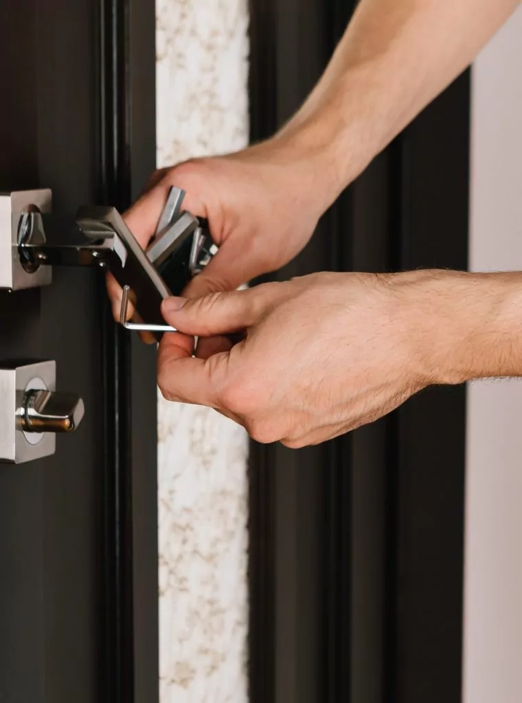 Ein Fachmann vom Schlüsseldienst Essen justiert einen modernen Türgriff an einer dunklen Holztür für eine reibungslose Funktion.